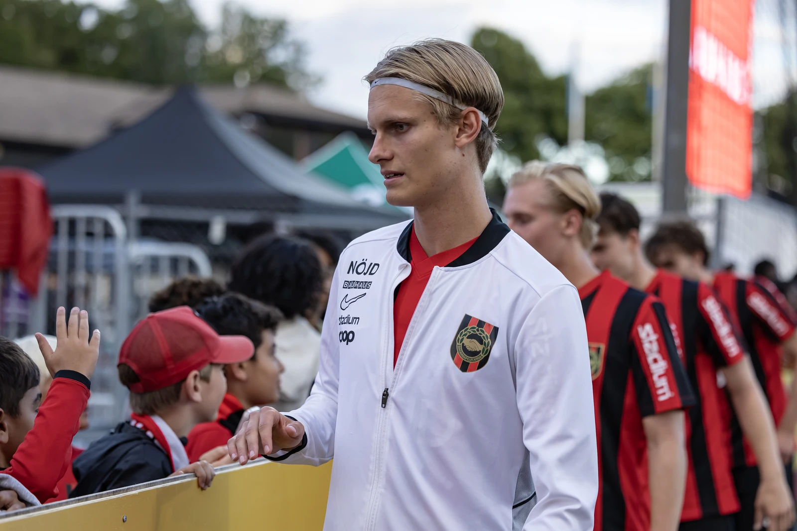 Elton i Brommapojkarnas matchmiljö, på väg förbi barn som sträcker fram händerna.